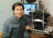 Xiaofei Fan, a post-doctoral fellow at MU, sits next to the computerized binocular infrared pulillography device, a machine that measures the time that the eye takes to react to a flash of light.  